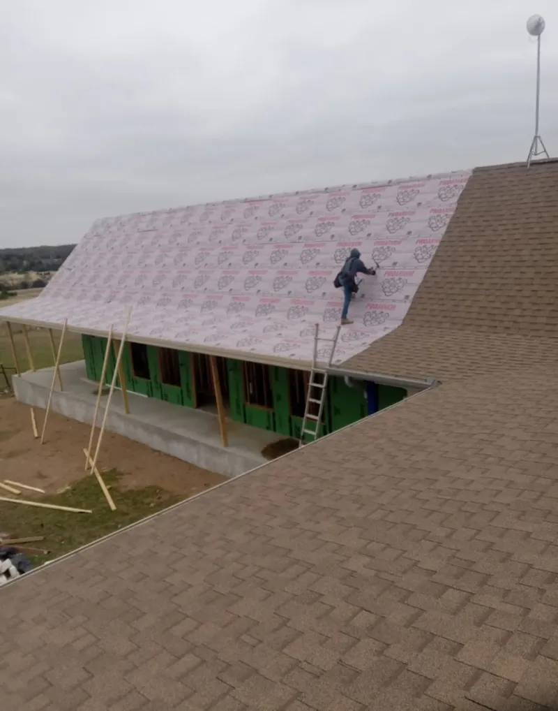 Worker preparing underlayment for a metal roof installation in Willingboro